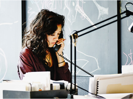 Woman in business attire taking a phone call at her desk
